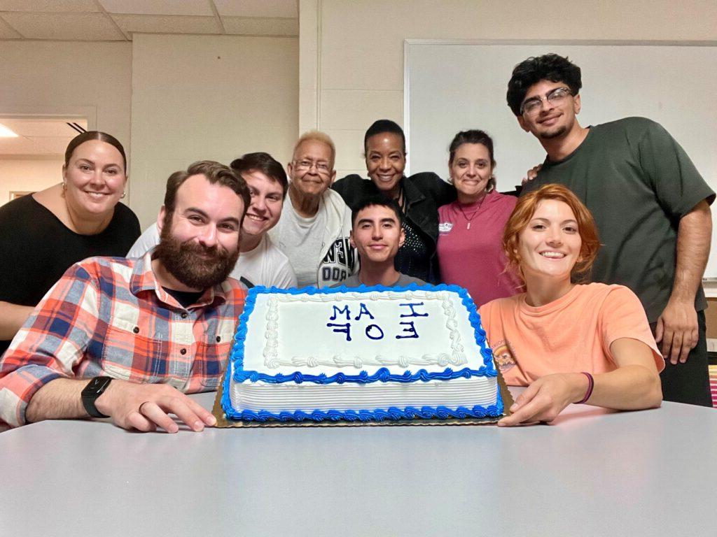 Group of EOF students and staff holding a cake that says "I am EOF"